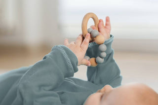 Baby greift einen Holzring und erkundet Form und Oberfläche