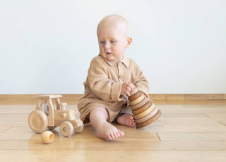 Baby verfolgt ein Holzspielzeug auf dem Boden mit den Augen