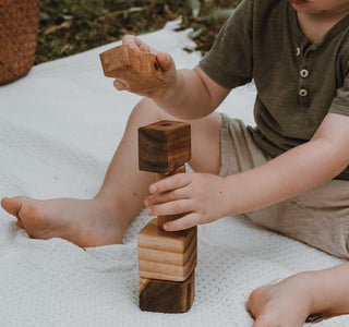 Baby erkundet Holzspielzeug mit allen Sinnen