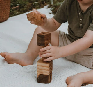 Kleinkind baut Turm mit Holzspielzeug 