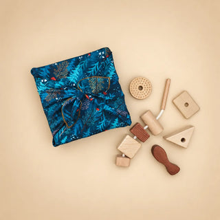 Holzspielzeug KAWI Senso ausgebreitet neben einem Geschenk zur Geburt verpackt in Furoshiki Geschenktuch