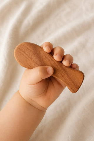 Babyhand greift eine geschwungene Holzform aus Kirschholz